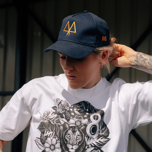 Person wearing a white t-shirt with a graphic design and a navy cap with a logo.