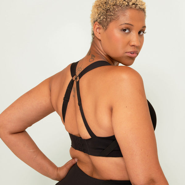 Woman wearing a black sports bra and leggings against a white background
