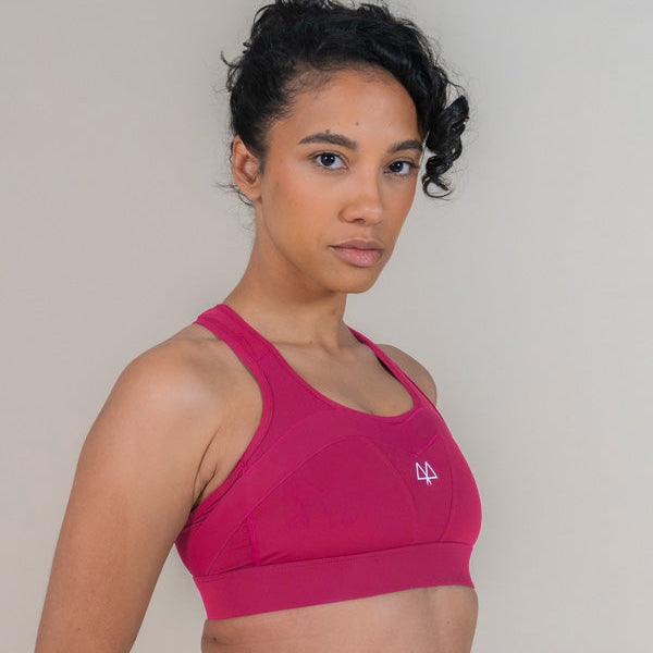 Woman wearing a pink sports bra with a logo on a plain background