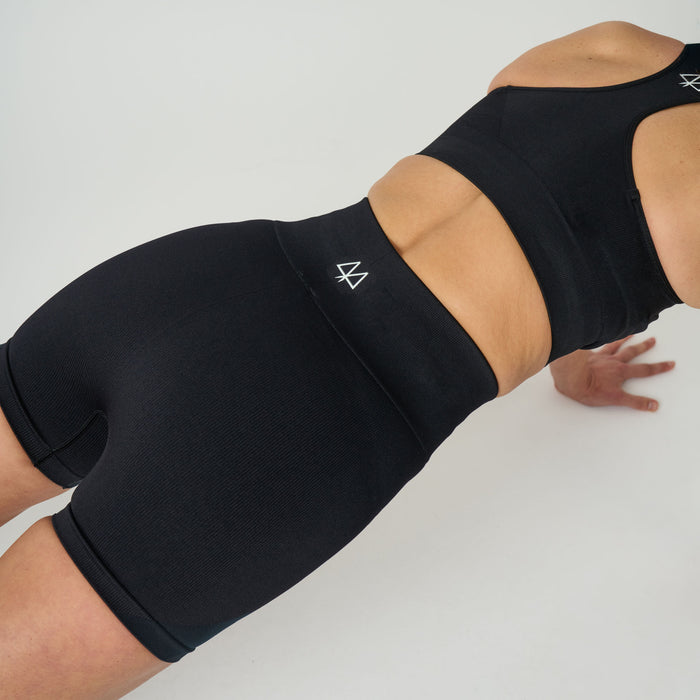 Person wearing black athletic shorts and top on a white background