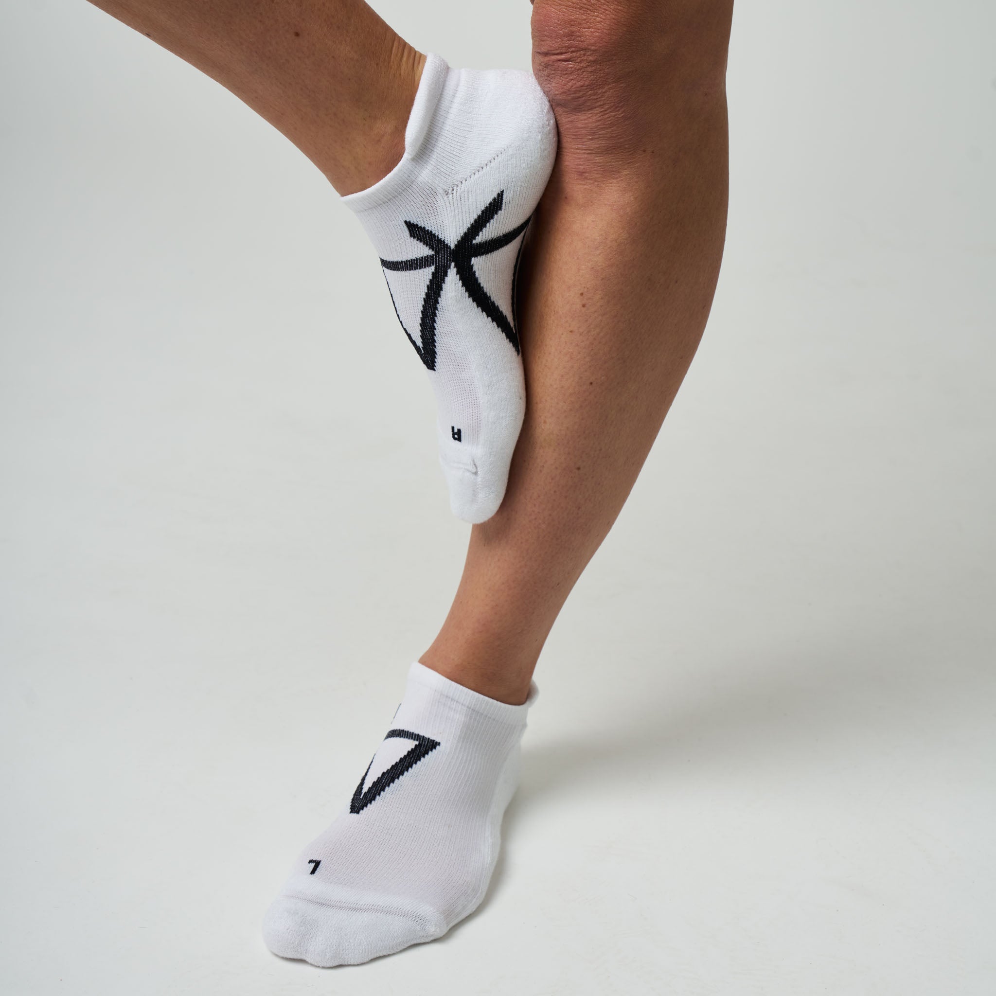 White socks with black designs worn by a person on a light gray background